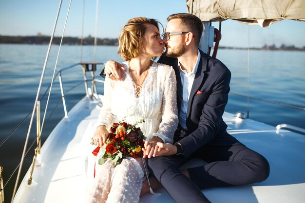 Una bella coppia di sposi su uno yacht il giorno del matrimonio all'aperto in mare insieme il giorno delle nozze