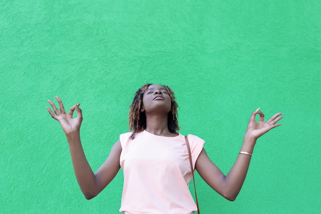 Una bella donna afroamericana medita contro un muro verde Spazio di copia Esercizio di rilassamento