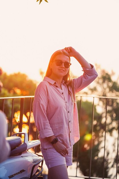 Una bella donna al tramonto sta in piedi su una terrazza con vista sul mare