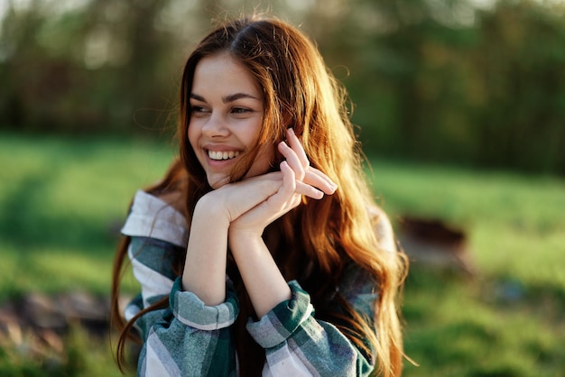 Una bella donna all'aperto in un parco verde ride e sorride mentre guarda nella telecamera al tramonto al sole Ritratto del primo piano Foto di alta qualità