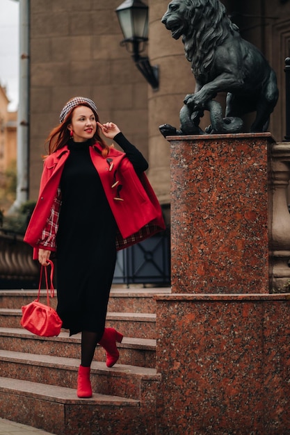 Una bella donna alla moda vestita con un elegante cappotto rosso con un'elegante borsetta rossa nella città d'autunno