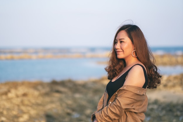 Una bella donna asiatica che cammina sulla spiaggia in riva al mare