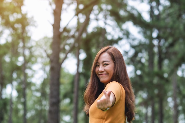 Una bella donna asiatica che fa il segno della mano del mini cuore nel parco