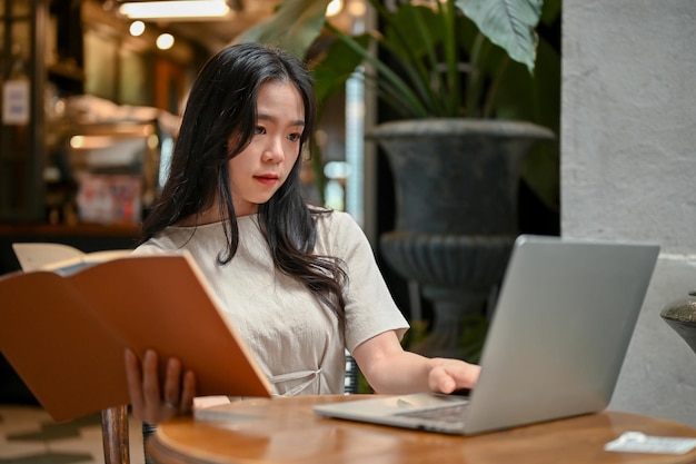 Una bella donna asiatica che lavora a distanza in un bellissimo caffè in città