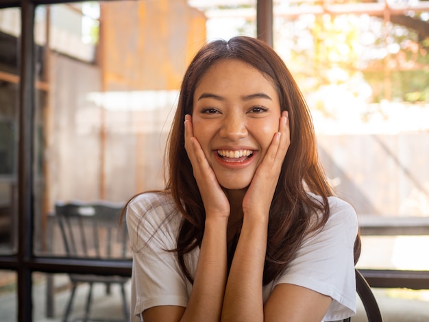 Una bella donna asiatica con i capelli lunghi che indossa una camicia bianca a maniche corte, sorridendo allegra