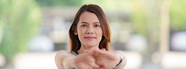 Una bella donna asiatica in abiti sportivi che fa stretching prima degli allenamenti a casa