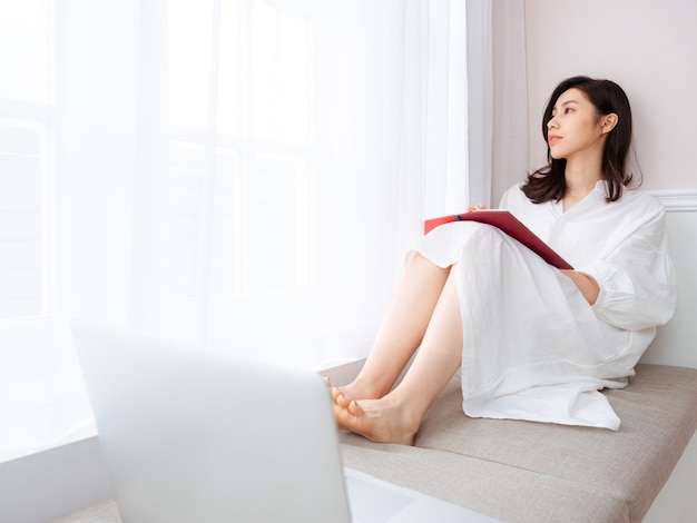 Una bella donna asiatica scrive qualcosa in un libro