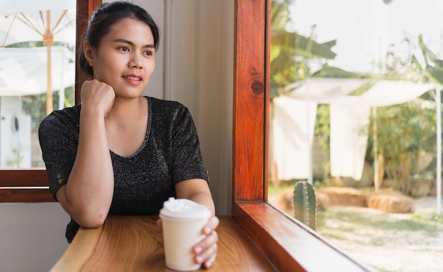 Una bella donna asiatica si siede al bancone del bar nella caffetteria con in mano una carta rilassata nella caffetteria