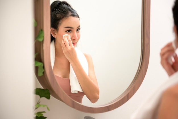 Una bella donna asiatica si sta lavando e pulendosi la faccia.