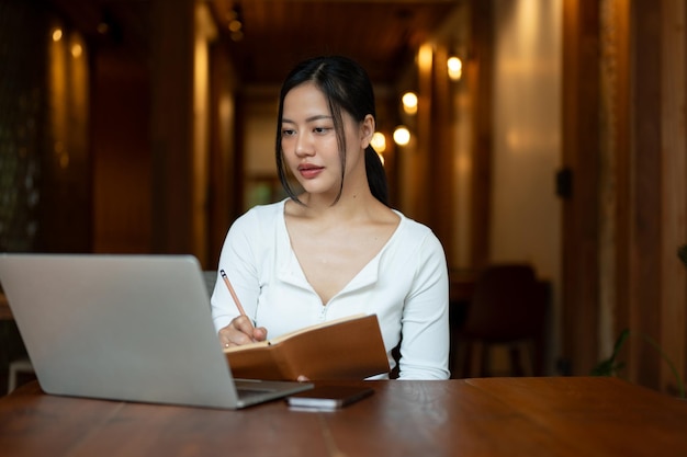 Una bella donna asiatica studia online o lavora da remoto in un bar