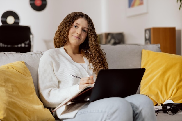 Una bella donna attraente innamorata di un uomo appena incontrato è seduta su un divano con un laptop