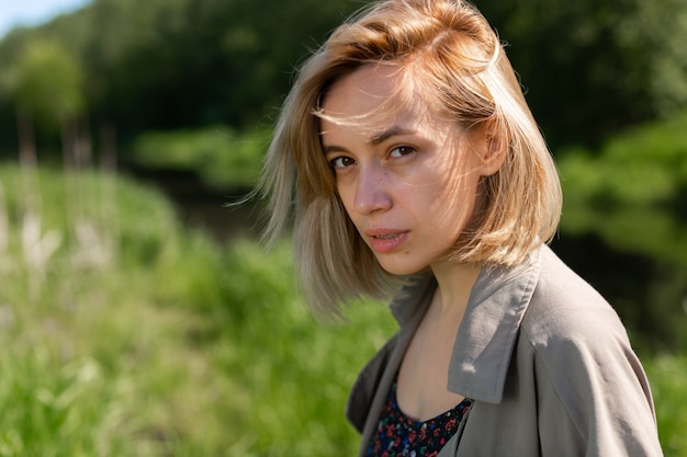 Una bella donna bionda con una camicia grigia si trova su un prato