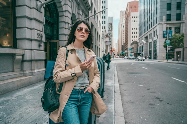 una bella donna che aspetta e usa il suo cellulare mentre aspetta nei negozi in strada.