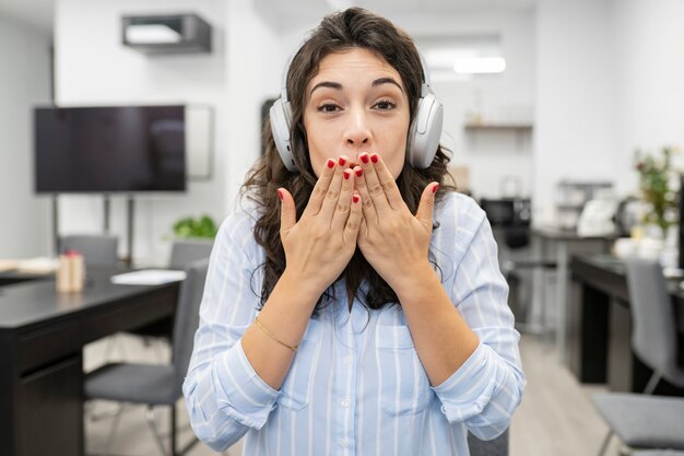 Una bella donna che lavora in ufficio, indossa le cuffie e fa una videochiamata