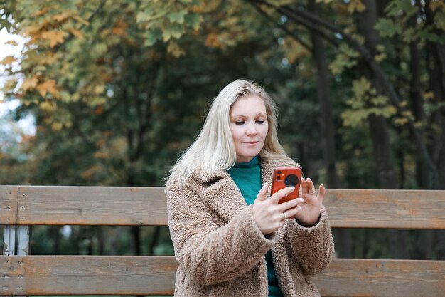 Una bella donna che parla al telefono in un parco autunnale