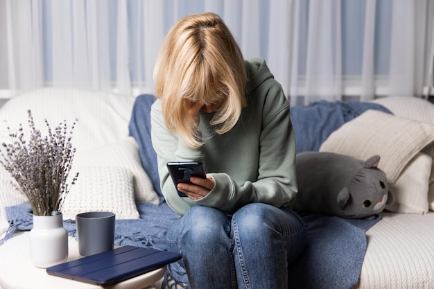 Una bella donna che si riposa sul divano usando applicazioni su smartphone una donna che chatta in messenger