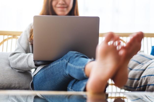 Una bella donna che usa e lavora al computer portatile mentre è seduta su un divano a casa