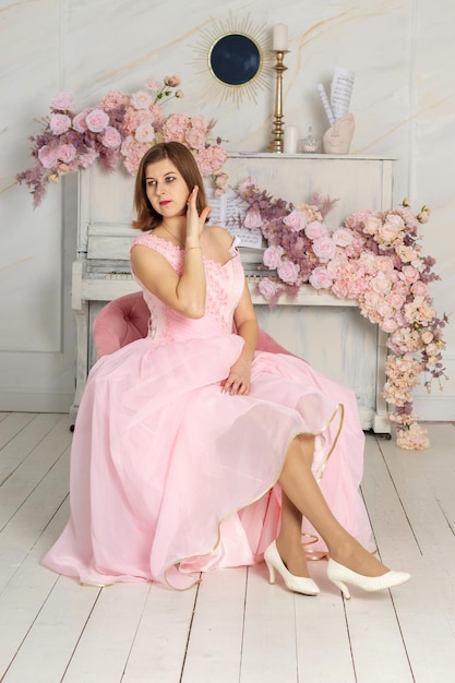 Una bella donna con un lungo vestito rosa in una sala con fiori La ragazza è bella PRIMAVERA PHOTOSESSION