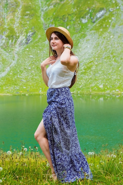 Una bella donna con un vestito e un cappello si trova vicino al lago Balea