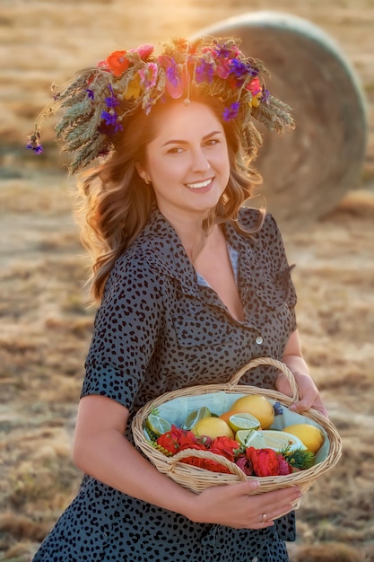 Una bella donna con una corona in testa e un cesto di frutta fresca