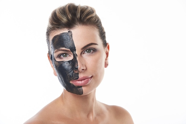 Una bella donna con una maschera nera purificante su un lato del viso