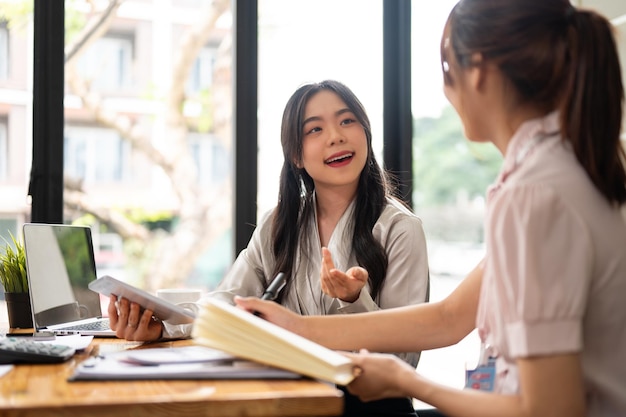 Una bella donna d'affari asiatica sta discutendo di lavoro e condividendo le sue idee con il suo collega