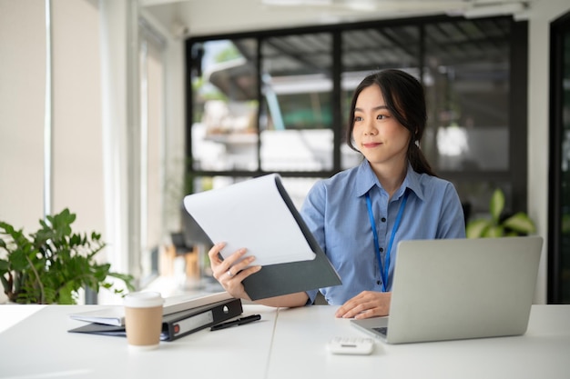 Una bella donna d'affari asiatica sta lavorando ai suoi compiti aziendali alla sua scrivania