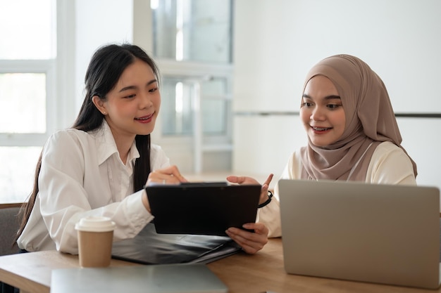 Una bella donna d'affari asiatica sta lavorando con una collega musulmana asiatica nella sala riunioni