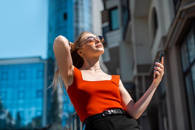 Una bella donna d'affari con un telefono cellulare sta camminando negli edifici del centro città