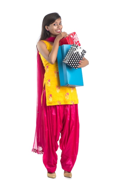 Una bella donna in posa con un sacchetto della spesa e scatole regalo su un bianco.