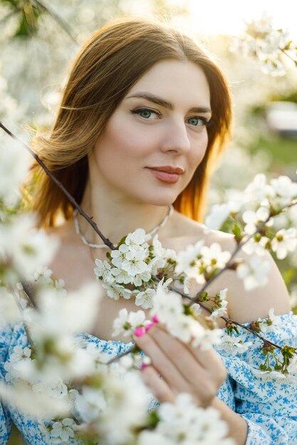 Una bella donna in un abito blu in un giardino fiorito di primavera Una dolce donna in un abito estivo leggero