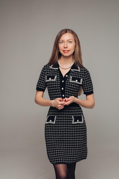 Una bella donna in un vestito nero in studio su sfondo grigio