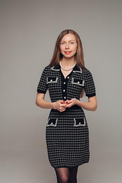 Una bella donna in un vestito nero in studio su sfondo grigio