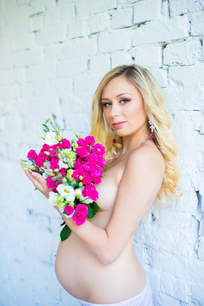 Una bella donna incinta con un mazzo di fiori in attesa del bambino Gravidanza