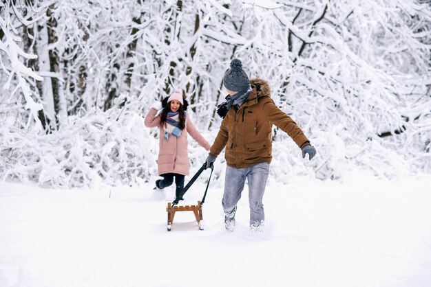 Una bella donna incinta in abiti pesanti lancia palle di neve al marito