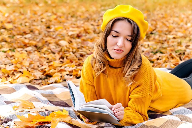 Una bella donna legge un libro in autunno Ritratto di una splendida bruna leggendo un libro nel parco