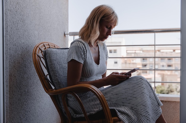 Una bella donna parla al telefono sulla terrazza soleggiata