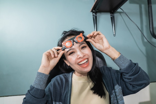 Una bella donna posa tenendo i bicchieri di misurazione che vengono utilizzati in una stanza in una clinica oculistica