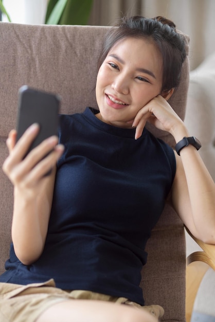 Una bella donna siede su una comoda poltrona e si diverte a guardare i contenuti online sui social media