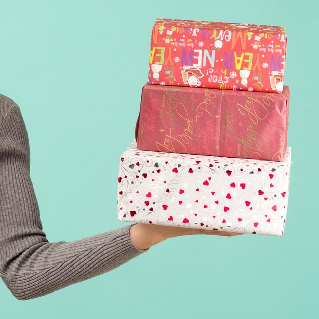 Una bella donna sorridente in un abito grigio, tiene in mano i regali. Celebrazione di Natale o Capodanno