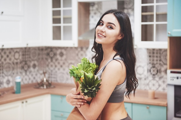 Una bella donna sportiva con frutta e verdura fresca in cucina