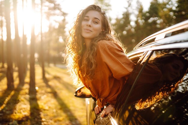 Una bella donna viaggiatrice si riposa e si gode il tramonto in macchina Turismo di stile di vita attivo