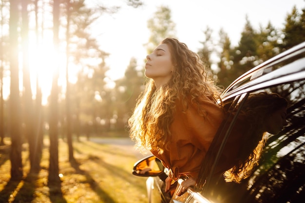 Una bella donna viaggiatrice si riposa e si gode il tramonto in macchina Turismo di stile di vita attivo