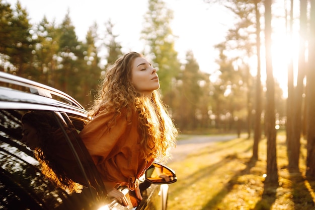 Una bella donna viaggiatrice si riposa e si gode il tramonto in macchina Turismo di stile di vita attivo