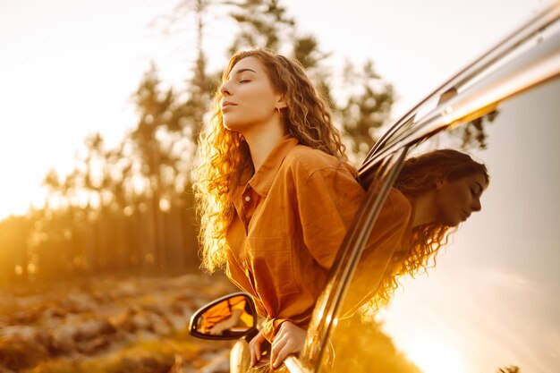 Una bella donna viaggiatrice si riposa e si gode il tramonto in macchina Turismo di stile di vita attivo