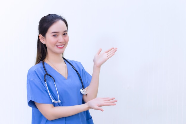 Una bella dottoressa asiatica in uniforme blu si alza in piedi e sorride mentre indica la cima