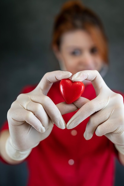 Una bella dottoressa caucasica che tiene un cuore rosso isolato