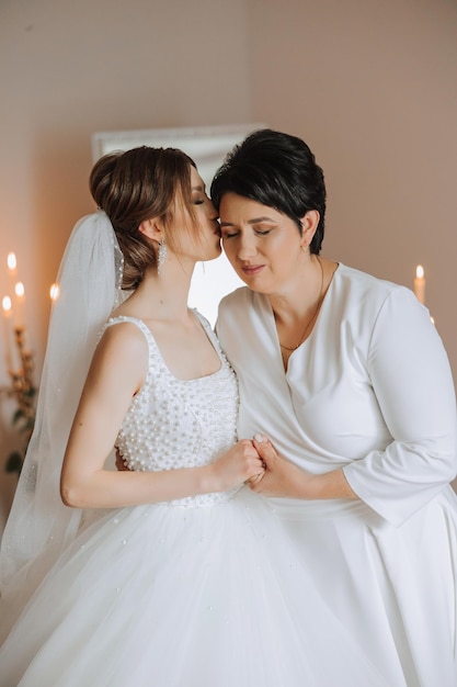 Una bella e felice madre e sua figlia la sposa sono in piedi l'una accanto all'altra il giorno migliore per i genitori momenti teneri al matrimonio