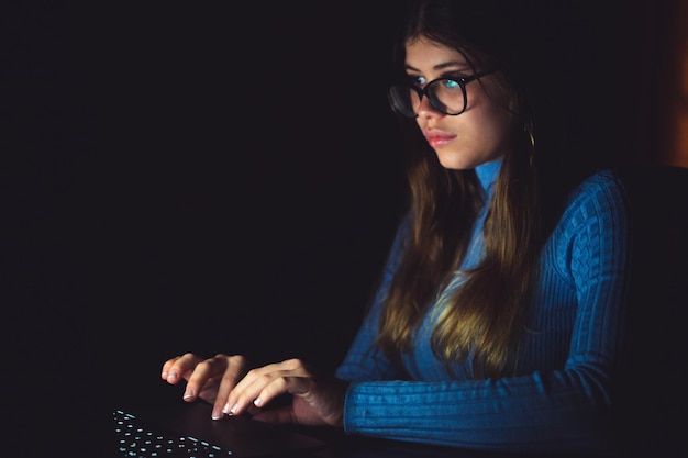 Una bella e giovane donna che utilizza il computer che lavora a tarda notte a casa Adolescente caucasico che indossa occhiali da vista che studia per un test