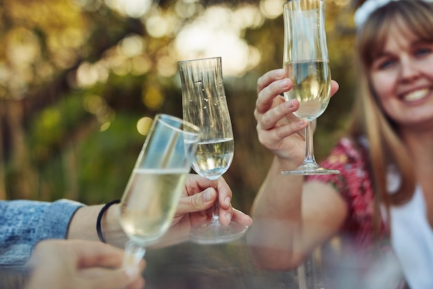 È una bella giornata per festeggiare e bere champagne Foto ritagliata di donne irriconoscibili che brindano con champagne a un tea party all'aperto